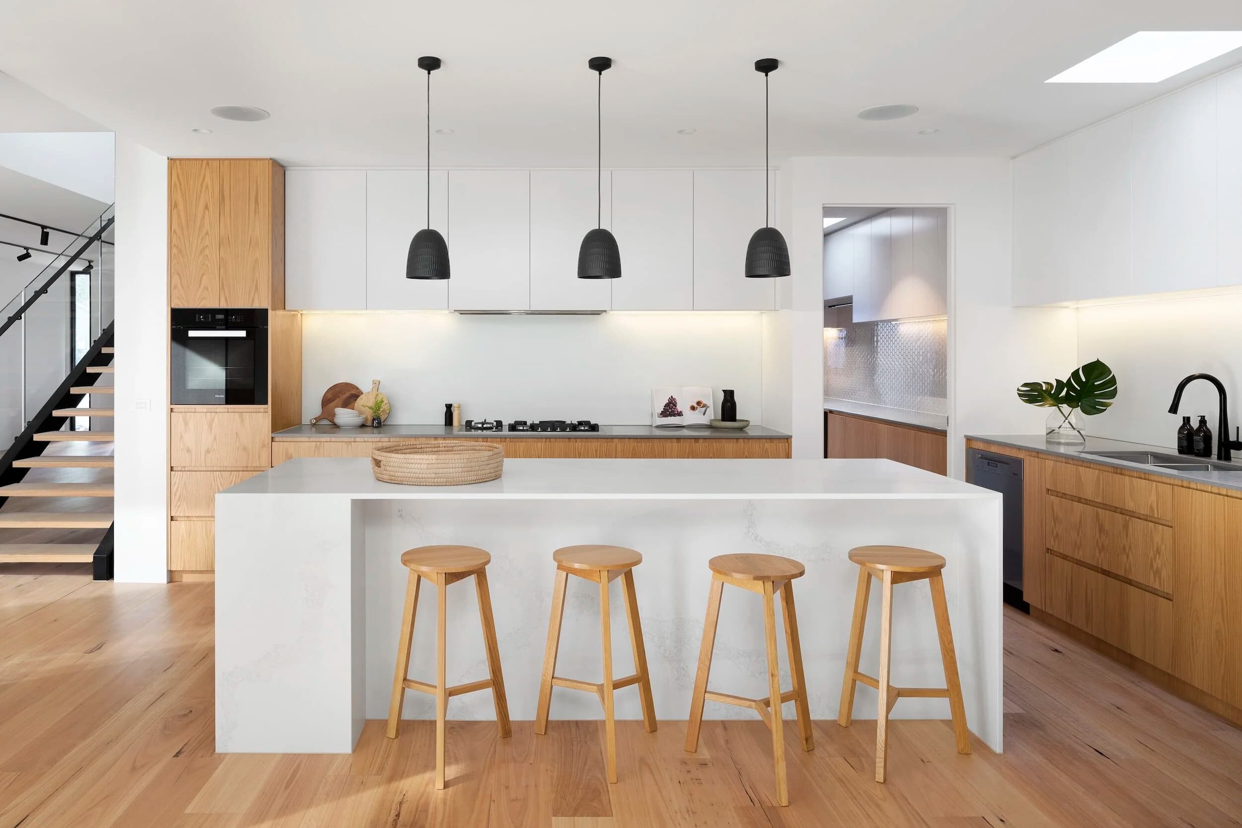 Two-tone Sydney kitchen with white and warm timber cabinetry and matte black pendants