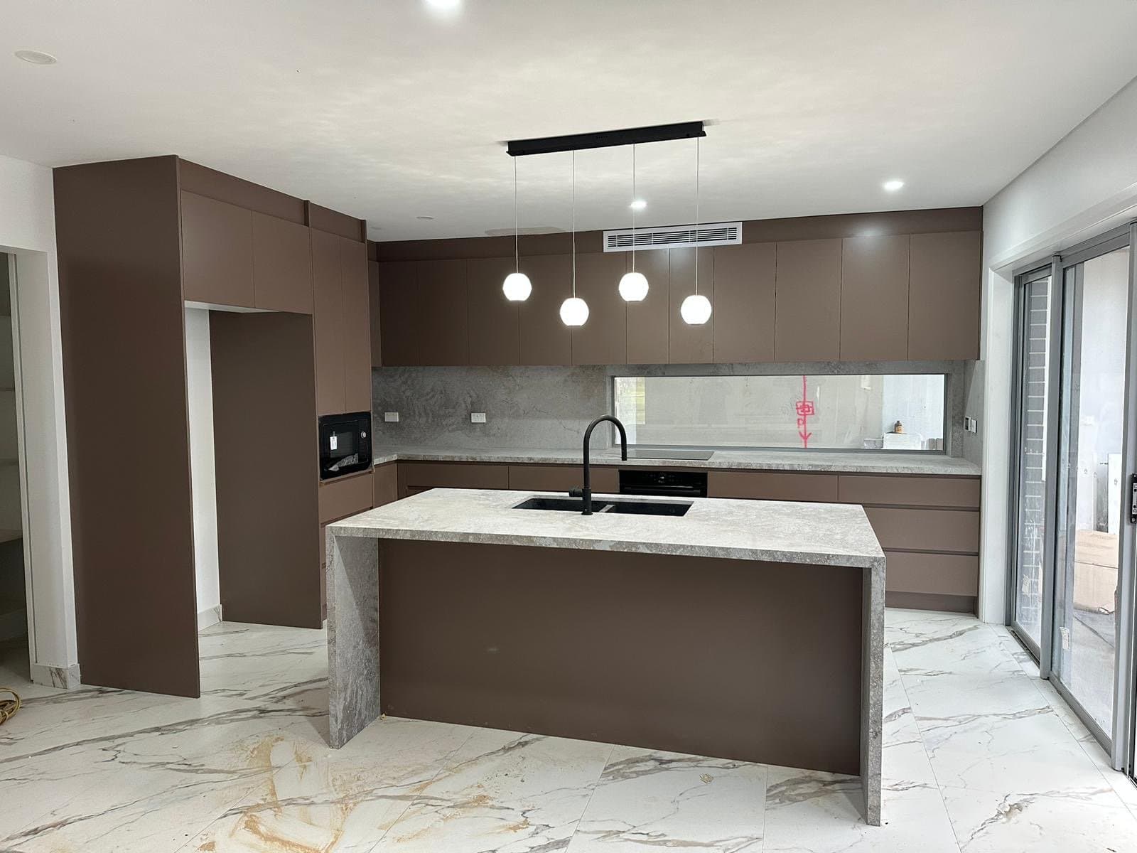 Warm timber-fronted kitchen with stone benchtops and integrated cooktop